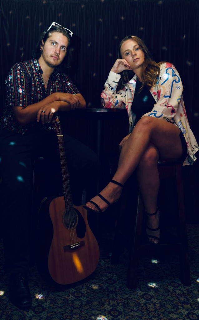 Sammie and Angelo with acoustic guitar at a bar stool